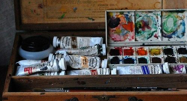 Artist's box containing oil paint tubes and watercolor paints.