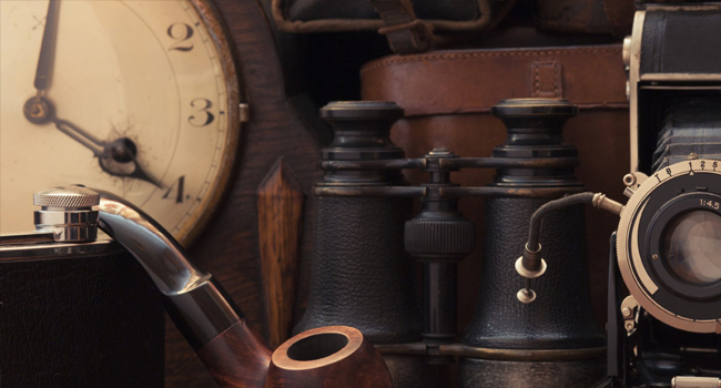 Old timey clock, camera, binoculars, pipe and flask.
